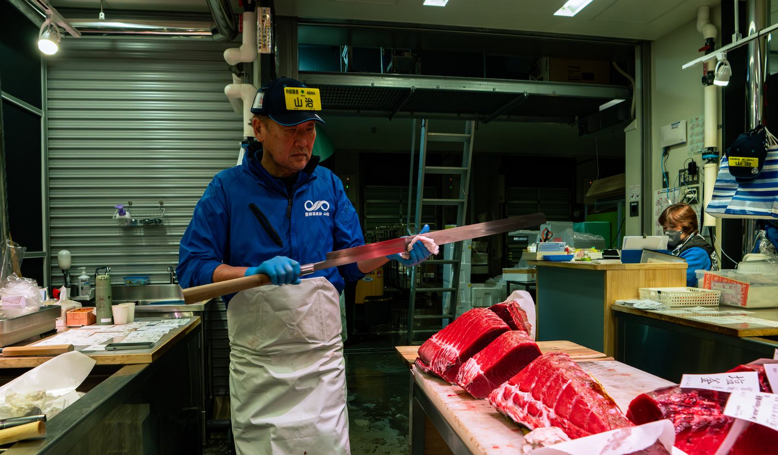 A Yamaharu tuna wholesaler with a long knife over bluefin loins